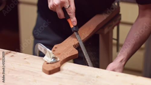 Luthier sanding the guitar neck of the acoustic guitar
