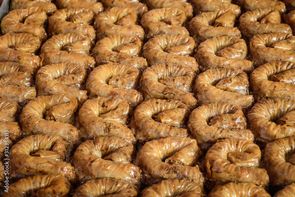 Close up of traditional oriental sweet pastry cookies known as backlava, Turkish desert with sugar, honey, walnuts and pistachio, in display at an weekend street food market, top view, soft focus