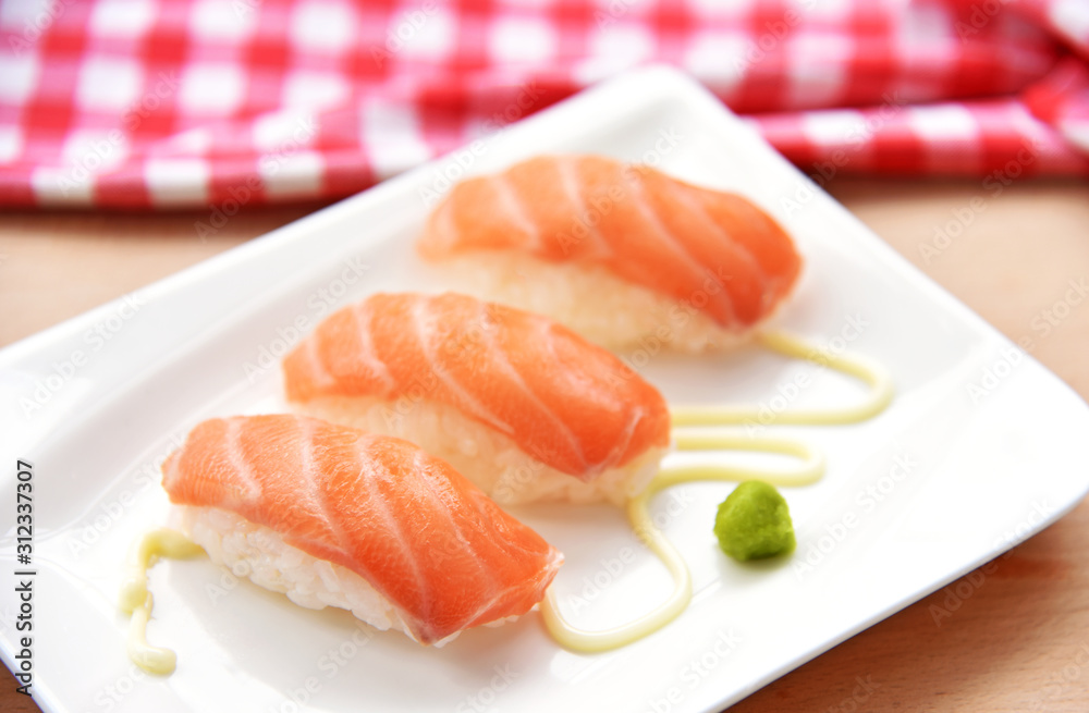 Homemade Salmon sushi on white dish with wasabi and mayonnaise on wooden floor Homemade Salmon sushi on white dish with wasabi and mayonnaise on wooden floor