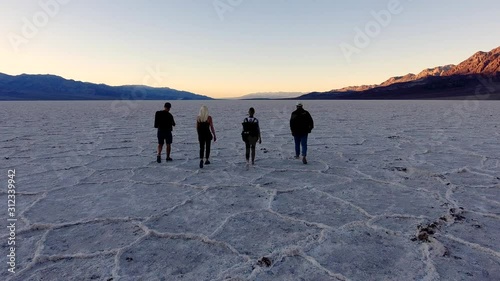 Concept of forward movement - youth people walking to their goals, scenery back view of four friends travelers walking on salt flats lake during breathtaking journey in Badwater Basin