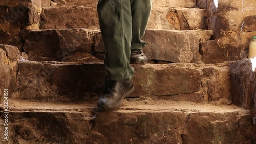 An unknown person goes down the stone stairs in an ancient fortress.