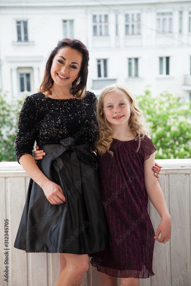 Portrait of a beautiful mom and daughter in family love dresses