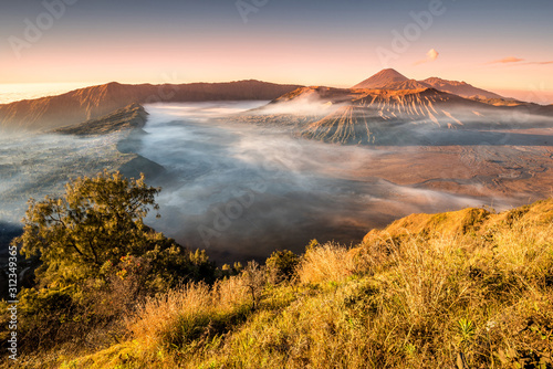 Colourful sunrise at the Mount Bromo, King Kong Hill Viewpoint. Wideangle panorama shot of amazing daybreak in Gunung Bromo active volcano in Java, Indonesia. Morning mist inversion photography.