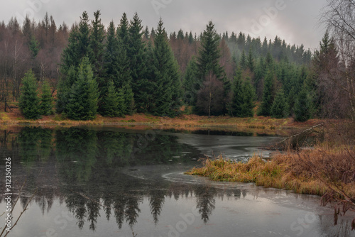 Ponds in Krusne hory mountains in winter cloudy evening