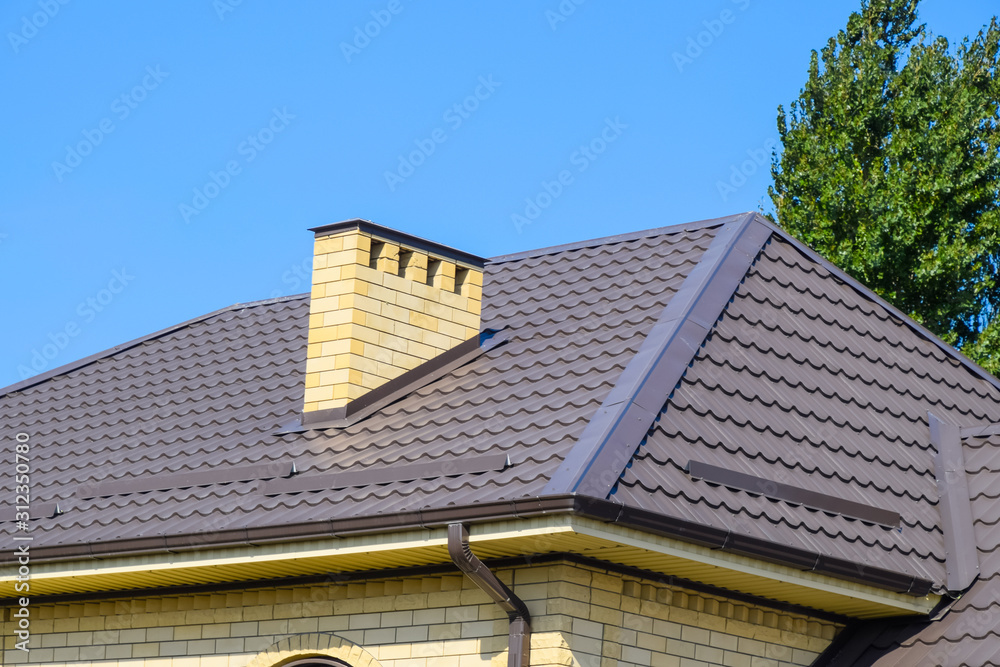 Brown corrugated metal profile roof. Chimney and ventilation of yellow brick.