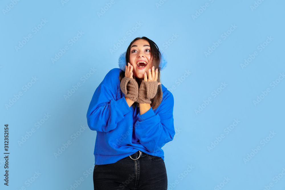 Happy smiling. Caucasian woman's portrait on blue studio background. Beautiful female model in warm clothes. Concept of emotions, facial expression, sales, ad. Winter mood, Christmas time, holidays.