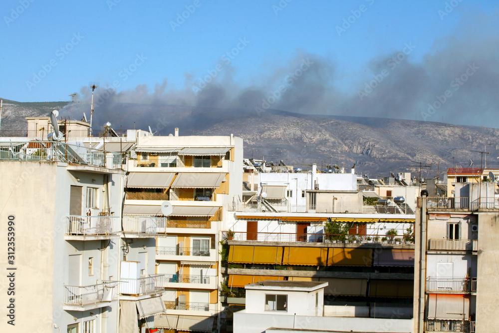 Fototapeta premium houses in athens with smoke of fire in backround