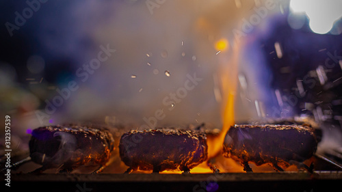 Fotografia meat grilling  on fire with smoke