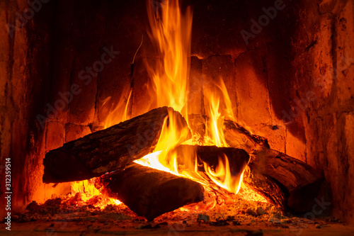 Fire in a fireplace with logs and flames creating a sense of warmth and coziness.