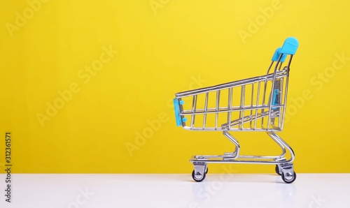 mini shopping trolley on yellow background. consumer concept