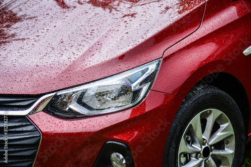 Detalhe do farol de um carro vermelho, molhado photo