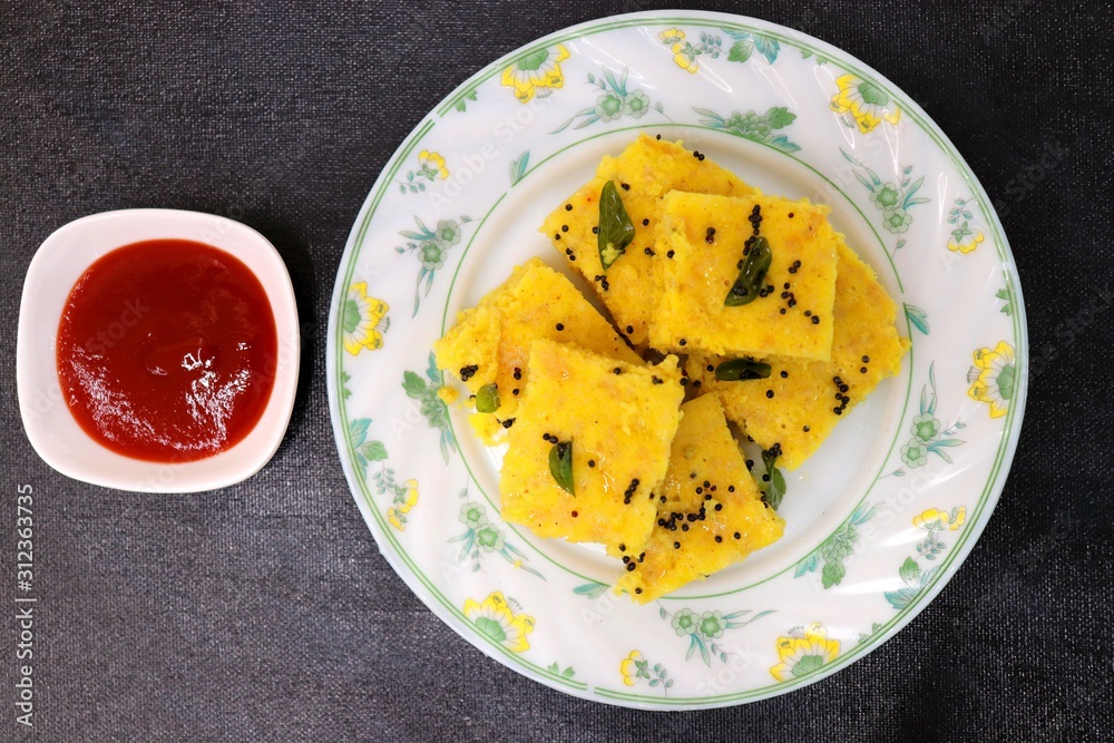 Gujarati Khaman Dhokla or Steamed Gram Flour cakes with spices tempering and garnished with coriander Gujarati Khaman Dhokla or Steamed Gram Flour cakes with spices tempering and garnished with coriander