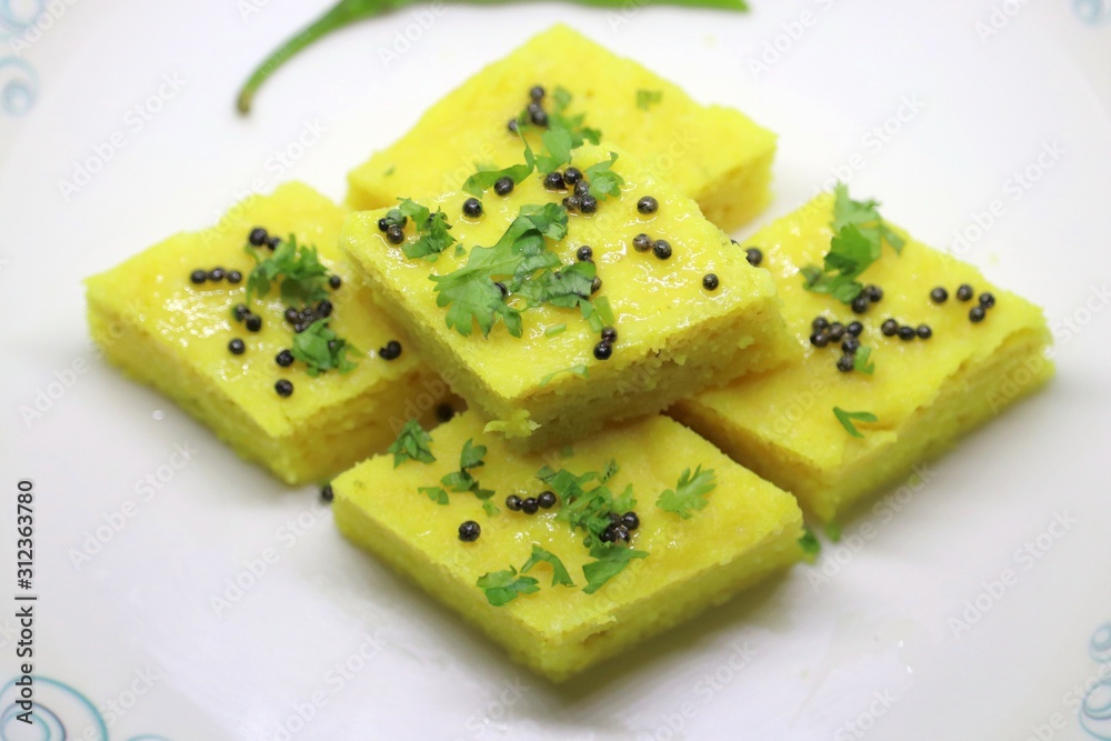 Gujarati Khaman Dhokla or Steamed Gram Flour cakes with spices tempering and garnished with coriander