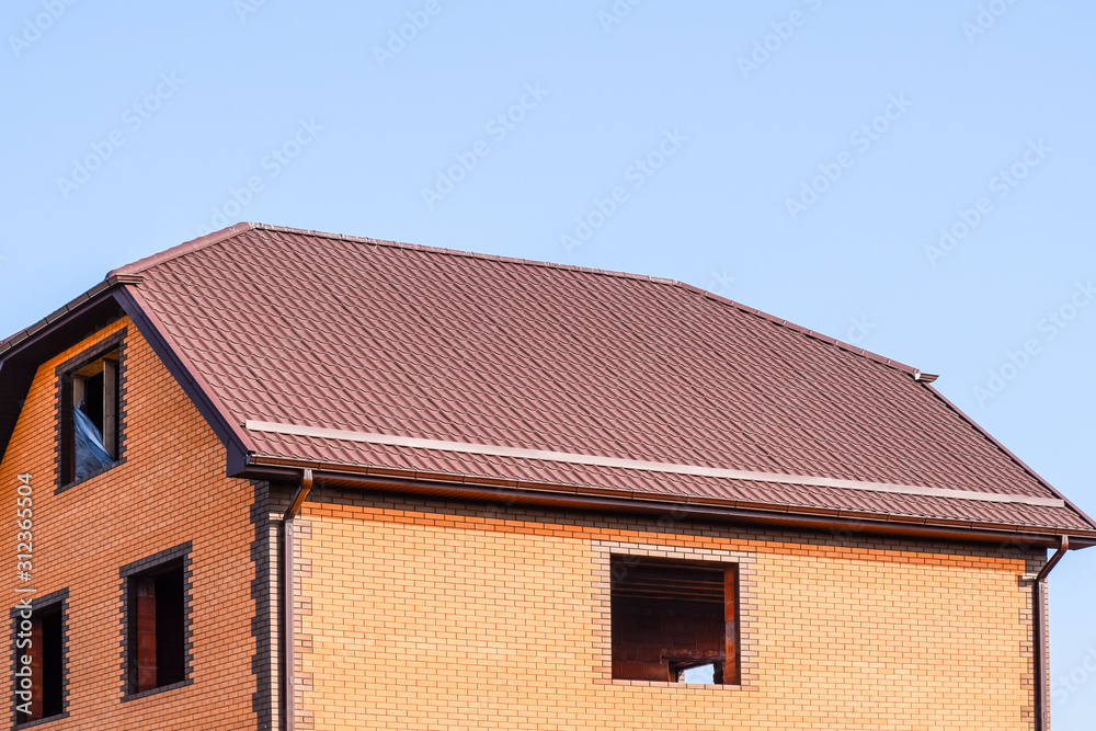 The house with plastic windows and a roof of corrugated sheet. Roofing of metal profile wavy shape on the house with plastic windows