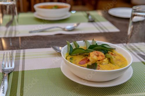 Seafood curry being served with shrimp on top