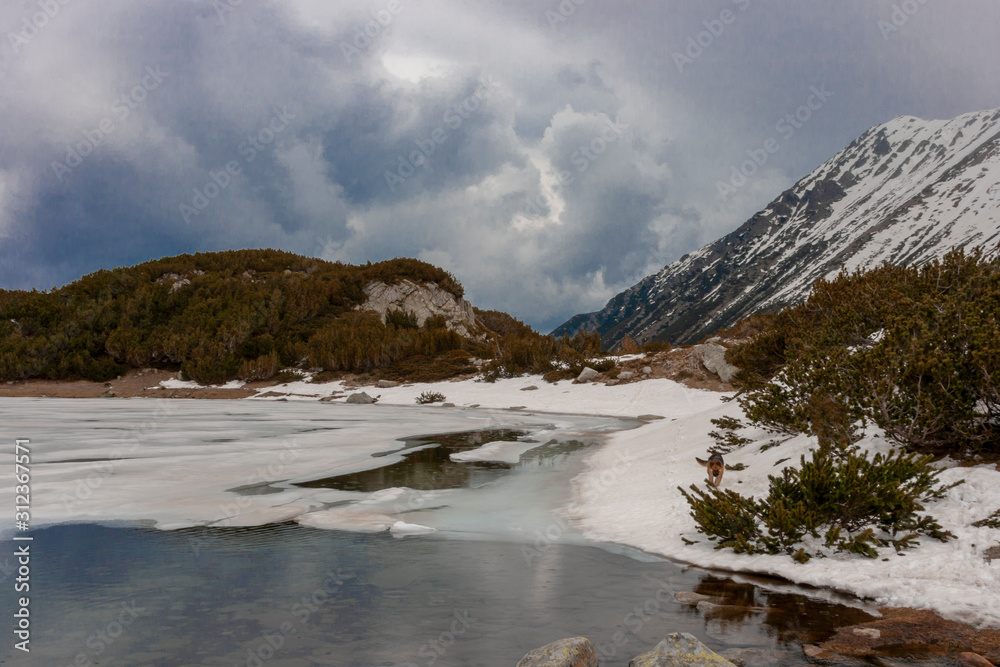 Landscape of giant lake turning into ice with snow covered mountains in the back and cloudy sky. Landscape of giant lake turning into ice with snow covered mountains in the back and cloudy sky.