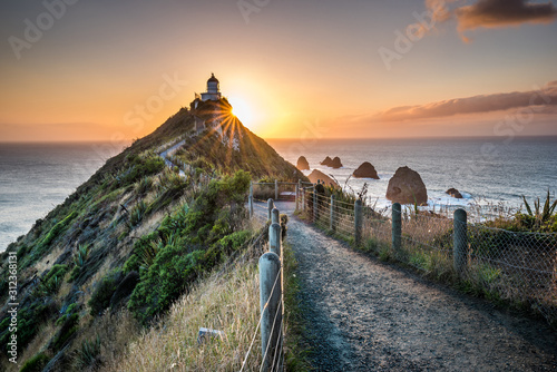 Nugget point Lighthouse. Beautiful sunrise landscape scenery. Walkway path to lighthouse in New Zealand.