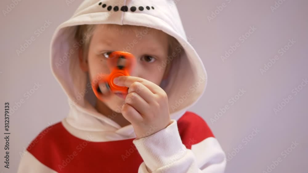 Funny blond child in nowman costume twists spiner on his nose. Portrait of boy on black background. 4K. Soothing toy. Autism. Exercise for Preschoolers Funny blond child in nowman costume twists spiner on his nose. Portrait of boy on black background. 4K. Soothing toy. Autism. Exercise for Preschoolers