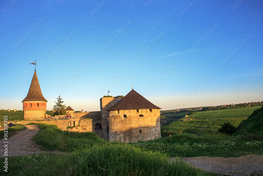 Summer landscape with old antique stone fortress Kamianets-Podilskyi at sunset, Ukraine