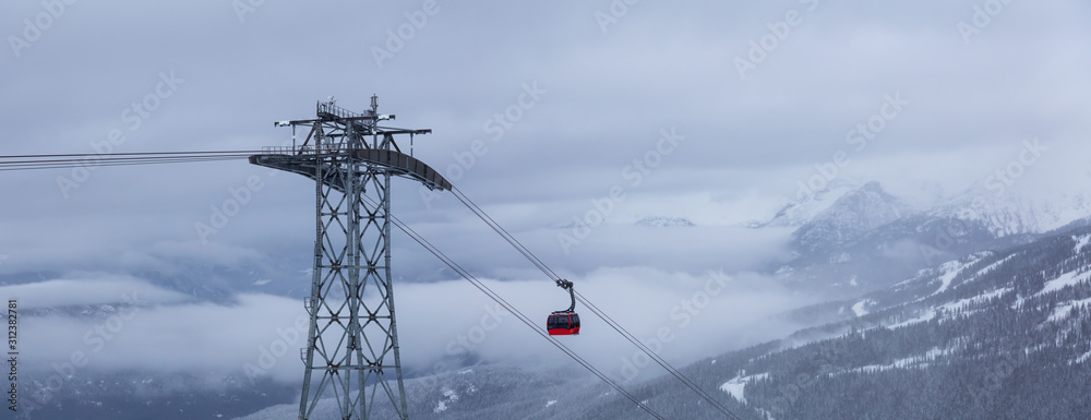 Whistler, British Columbia, Canada. Beautiful View of Peak to Peak Gondola with the Canadian Snow Covered Mountain Landscape during a cloudy and foggy winter day.