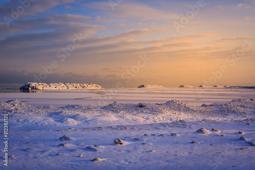 ice dunes and ice covered break walls along the shoreline of Lake Erie. Epic colorful dawn sky during winter