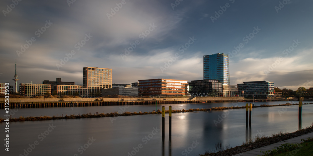 long exposure of the Überseestadt in Bremen, Germany with office buildings and cloudy sky during sunrise long exposure of the Überseestadt in Bremen, Germany with office buildings and cloudy sky during sunrise