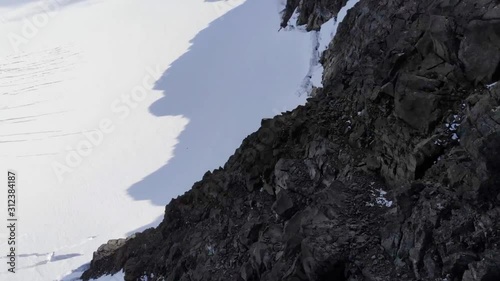 Aerial, tracking, drone shot, over hikers, standing on the highest point in Norway, the Galdhopiggen mountain,  tilting down towards a glacier, on a sunny, summer day, in Jotunheimen National park photo