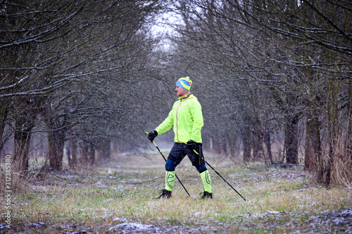Happy woman tourist trains nordic walking in the cold morning. Healthy concept.