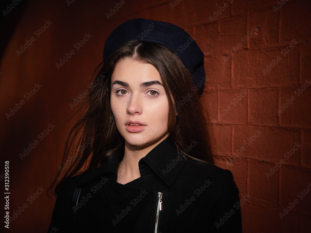 Mood contrasty portrait young elegant french style brown haired woman in beret and black leather jacket liten sun spot cinematic stock colour grading city street red bricks arc background Mood contrasty portrait young elegant french style brown haired woman in beret and black leather jacket liten sun spot cinematic stock colour grading city street red bricks arc background