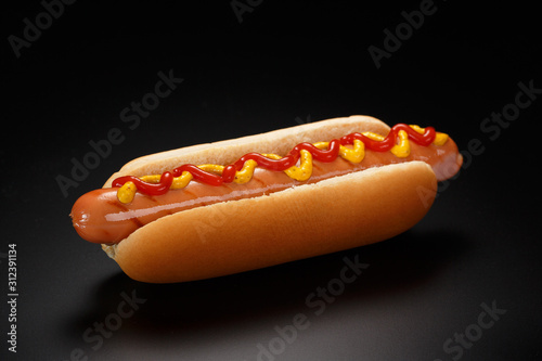 Classic hot dog with ketchup and mustard on a black background. photo