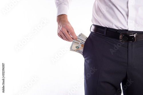 Businessman pulls out a pack of dollars from his trouser pocket closeup on a white background with space for text