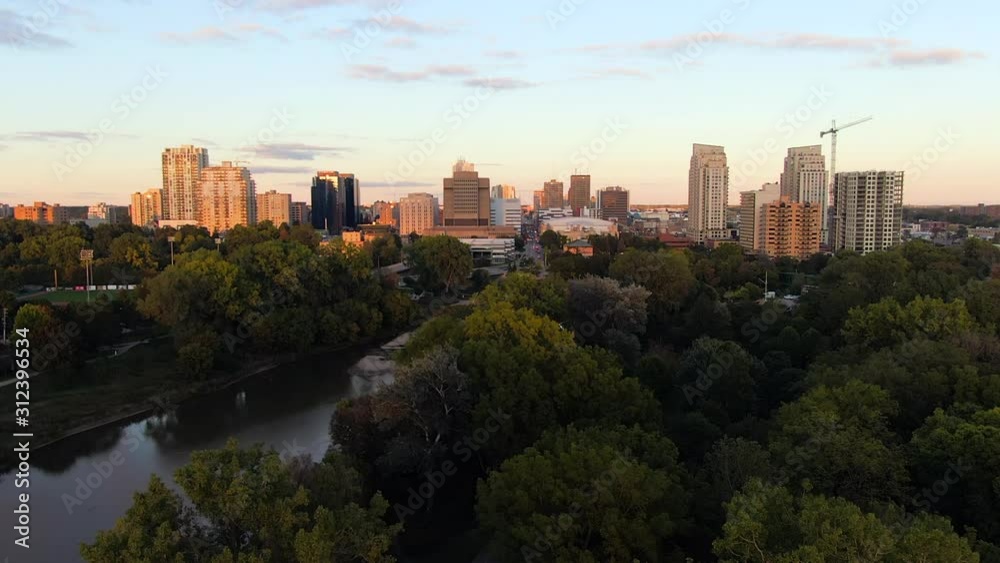 Rising aerial over green trees with London Ontario cityscape during sunset golden hour Rising aerial over green trees with London Ontario cityscape during sunset golden hour