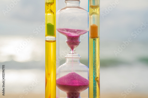 The hourglass passing time on the beach The hourglass in front of the bright blue sky with white clouds passing by Taking pictures in time lapse the concept of time, Phuket Thailand. photo