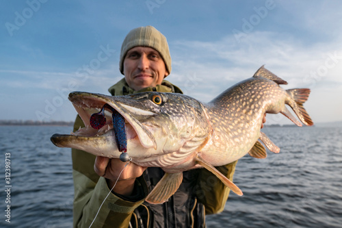 Happy fisherman with big pike fish. Boat fishing