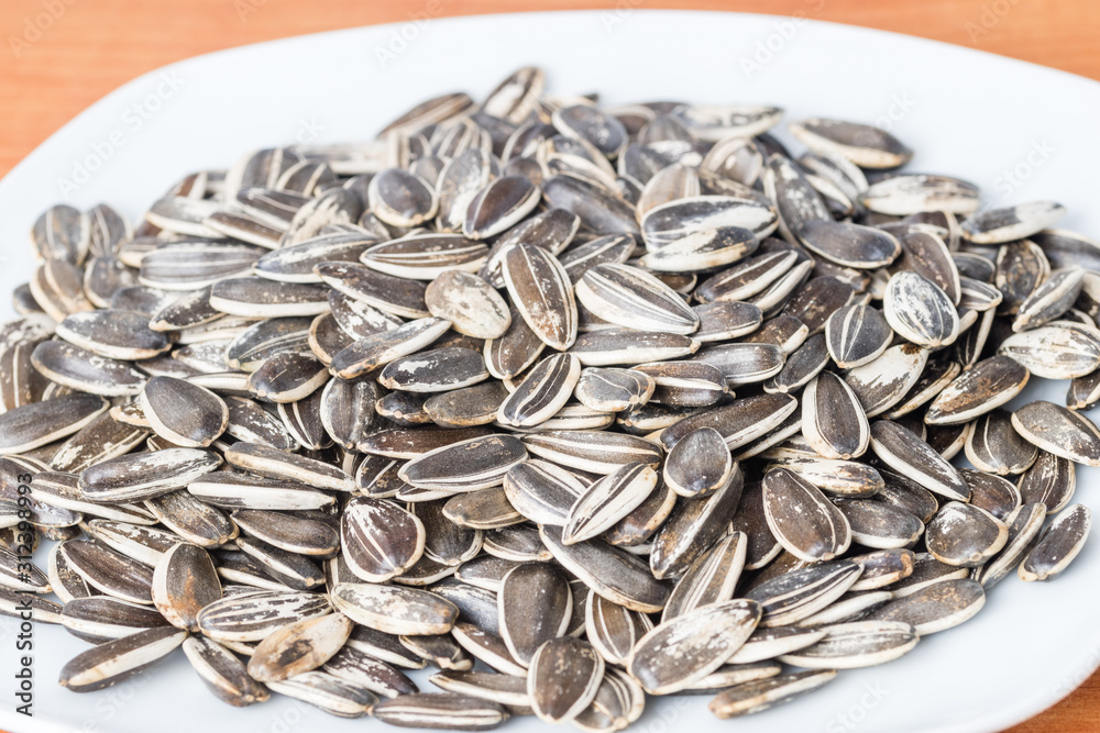 Unpeeled sunflower seeds on white plate. Unpeeled sunflower seeds on white plate.