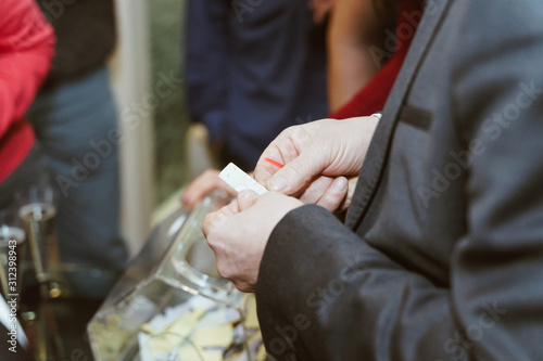 Hands take a ticket from the lottery drum