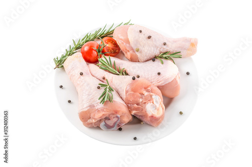 Raw chicken drumstick or legs in a plate with herbs and spices isolated on white background