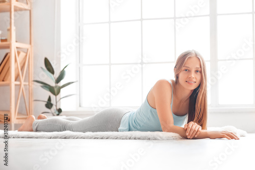 Weekend. Woman exercise at home lying on carpet smiling happy