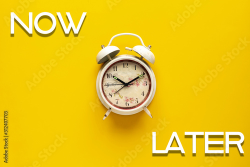  simple retro alarm clock on color background with words now and later, motivation idea