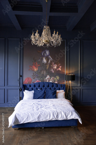 A modern bedroom with blue walls and a large bed with white pillows. The modern interior of the house.