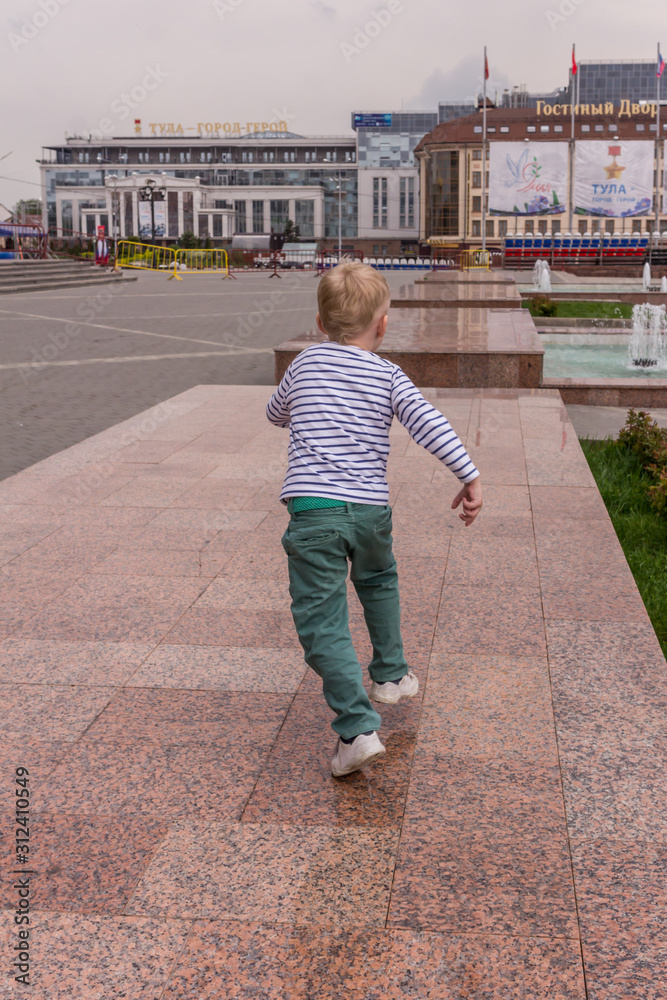 10.05.2019, Tula, Russia. A little boy ranning on square, back side view. Active lifestyle of kids.