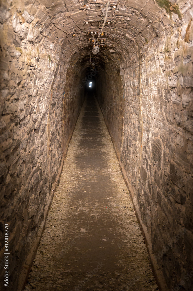 Dunkle gerade Höhle mit Licht am Ende des Tunnels als Metapher für Hoffnung und Durchhaltevermögen