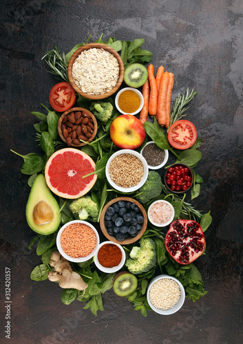 Healthy food clean eating selection: fruit, vegetable, seeds, superfood, cereals, leaf vegetable on rustic background © beats_