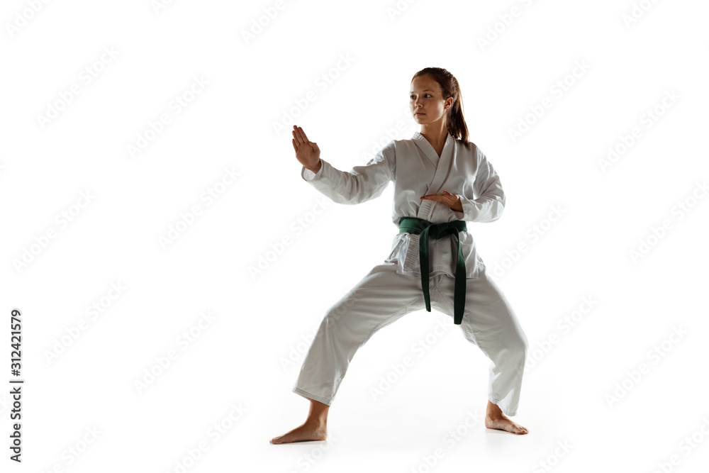Confident junior in kimono practicing hand-to-hand combat, martial arts. Young female mongol fighter with green belt training on white studio background. Concept of healthy lifestyle, sport, action. Confident junior in kimono practicing hand-to-hand combat, martial arts. Young female mongol fighter with green belt training on white studio background. Concept of healthy lifestyle, sport, action.