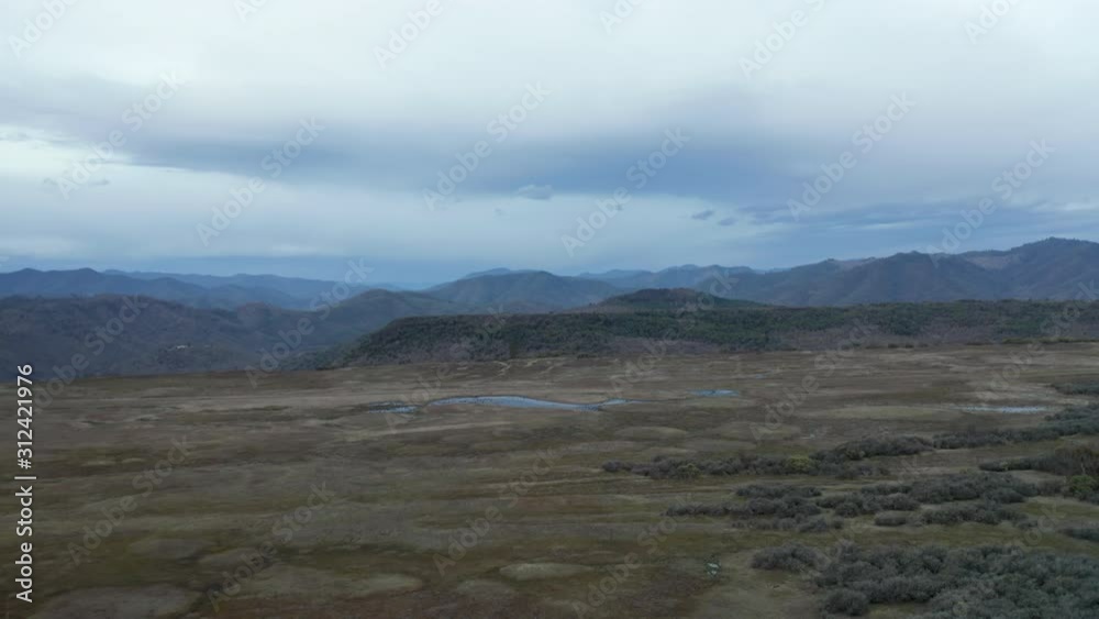 4k Aerial View Flying Backwards Over Flat Mountain with Big Mountains Behind 4k Aerial View Flying Backwards Over Flat Mountain with Big Mountains Behind