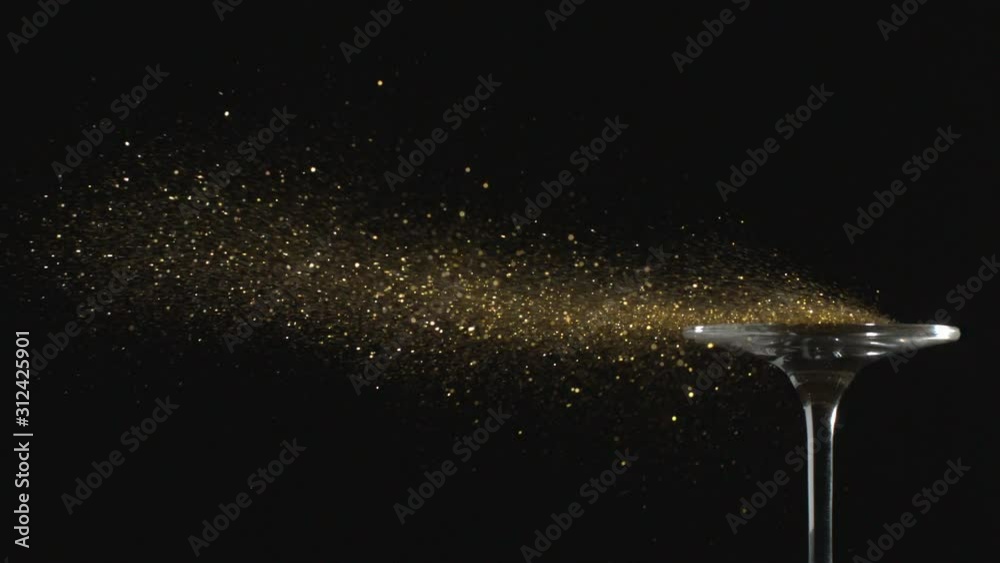 Golden Glitter Flying in the Air is Blown Away from a Glass in Slow Motion on Black Background