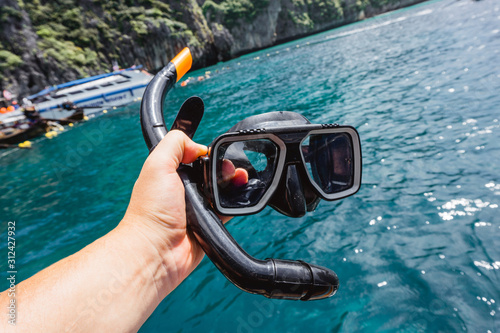 Konstfotografi Hand holding snorkeling mask and pipe over ocean water