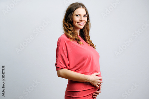 Elegant pregnant young woman on grey background. Awaiting a baby, Expectant mother. Pregnancy life.
