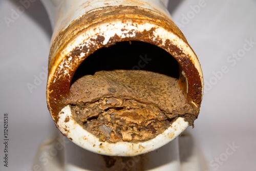 Foto The end of the toilet pipe, half of the diameter of which is clogged with deposits of urine