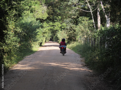 People riding a motorcycle on a dirt road. Rural road in the interior of Brazil